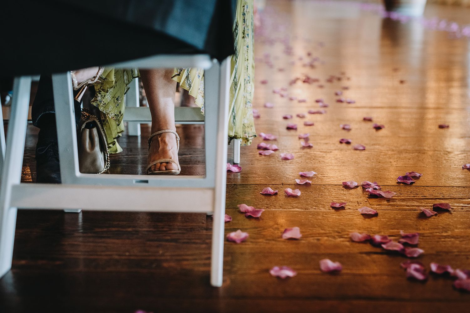 Pink rose petals scattered across a wooden floor create a romantic pathway through an indoor space.