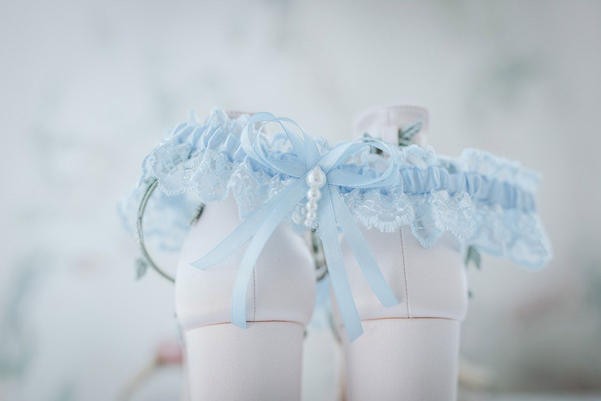 A delicate blue and white garter with lace trim and satin bow sits against a light background.