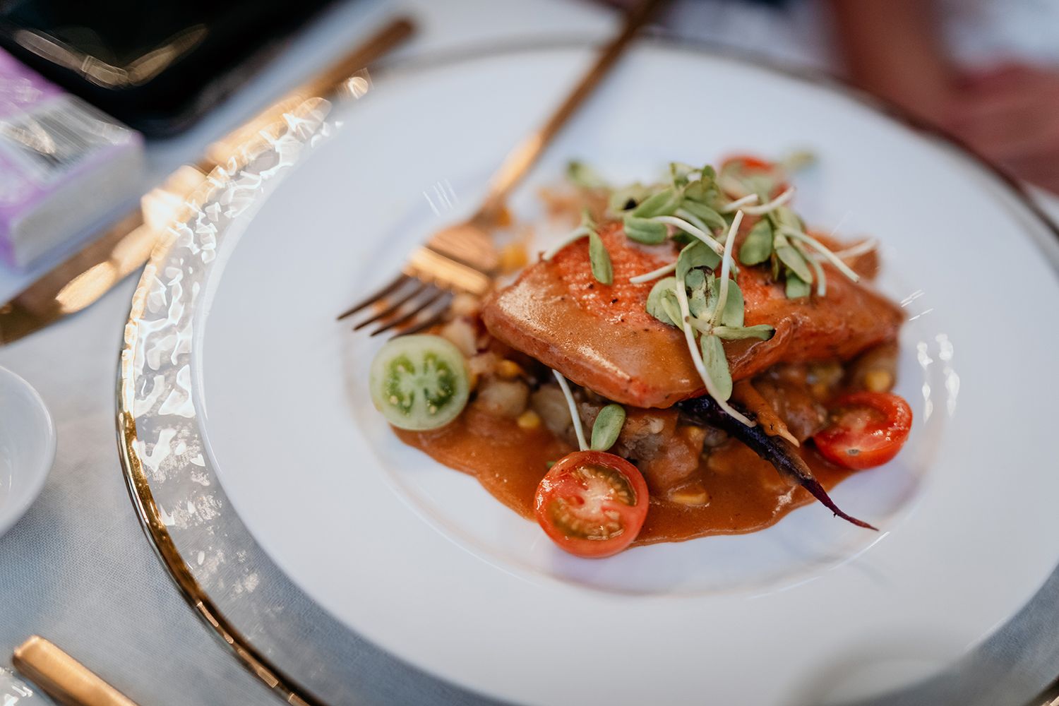 Elegant plated dishes featuring seared meats and delicate garnishes served on white plates in a fine dining setting.
