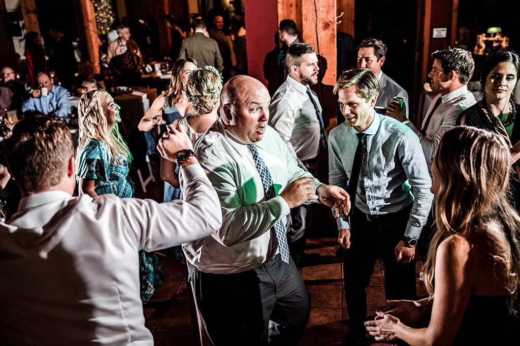 A group of people dancing together in a dimly lit venue with festive lighting and decorations.