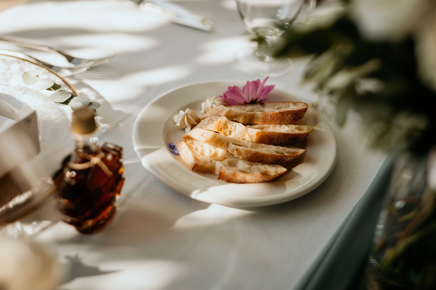 Sliced french toast topped with a pink flower garnish on a white plate with soft morning light. Summerhill Pryamid Winery wedding.