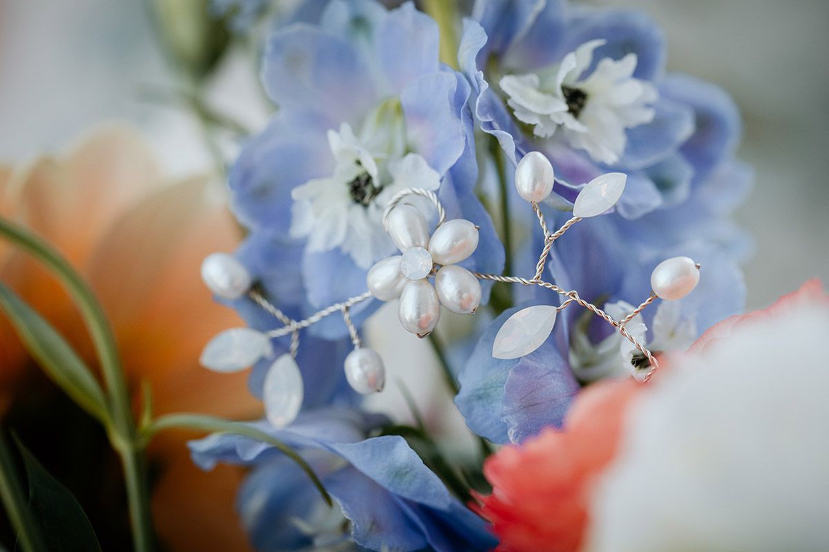 Delicate blue and white flowers in soft focus with coral accents in a floral arrangement.