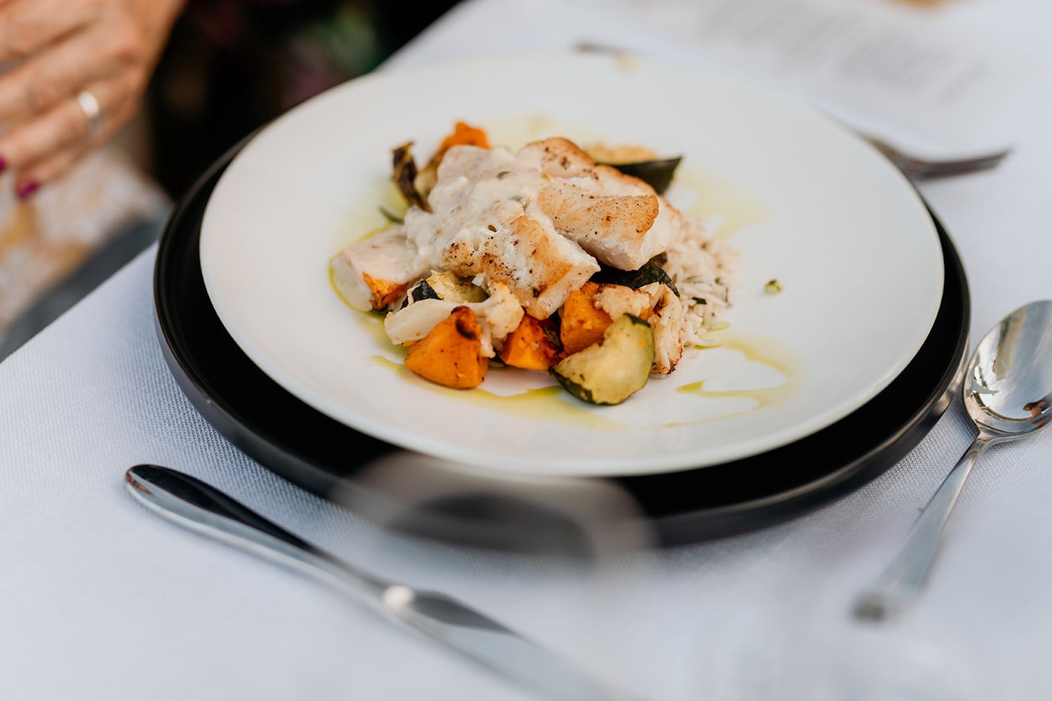 A series of elegant plated dishes arranged in a row on white plates with garnishes and sauces.