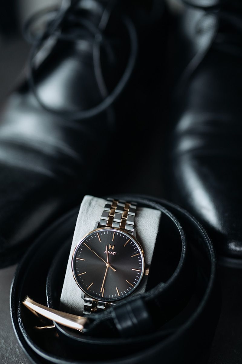 Sleek stainless steel wristwatch with black dial and rose gold accents photographed from multiple angles.