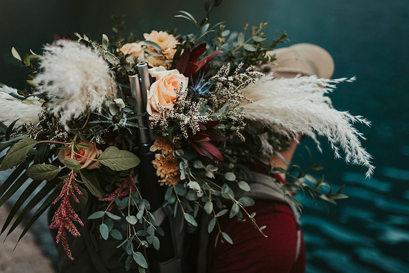 Elegant floral arrangements with pampas grass and peach roses against a moody teal backdrop create a romantic atmosphere.