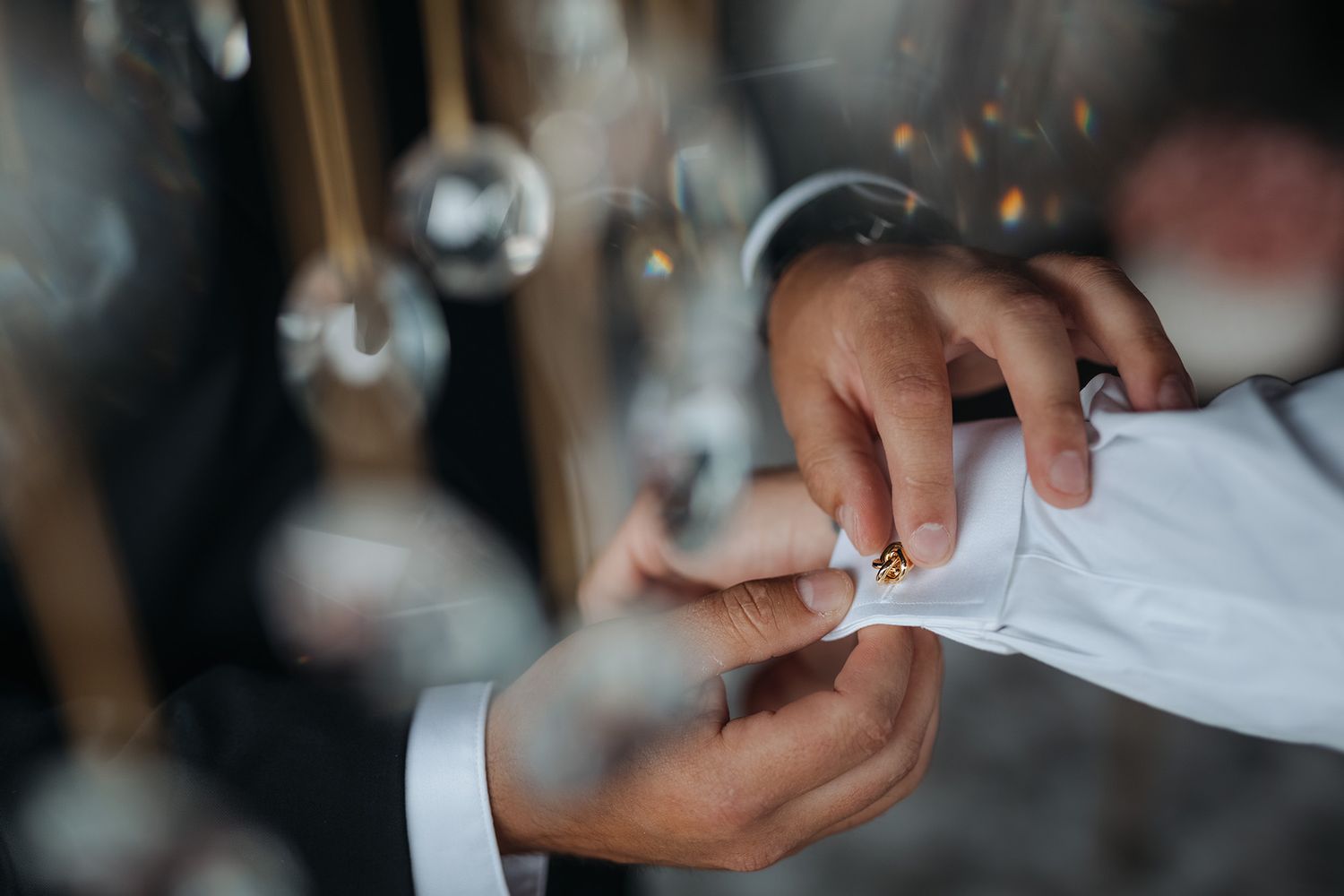 Close-up view of hands putting cuff-links in the cuffs of a white shirt.