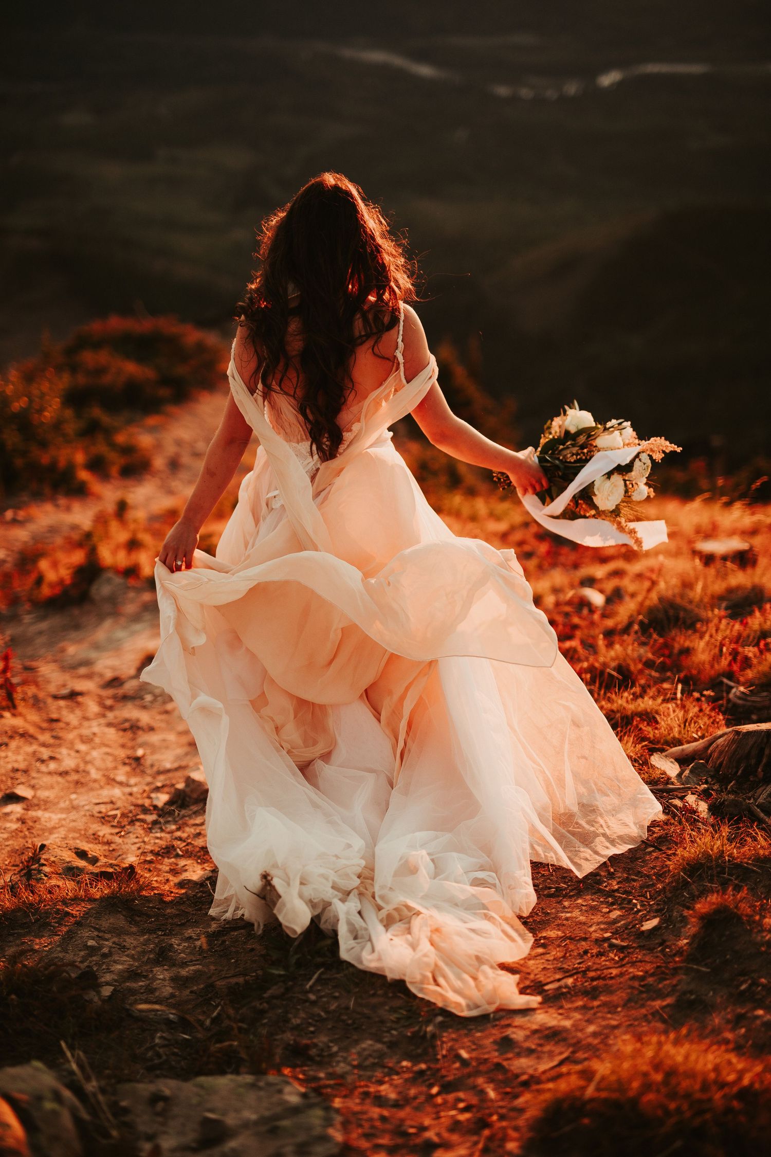 A flowing white wedding dress twirls gracefully against a backdrop of autumn leaves in warm sunset lighting.