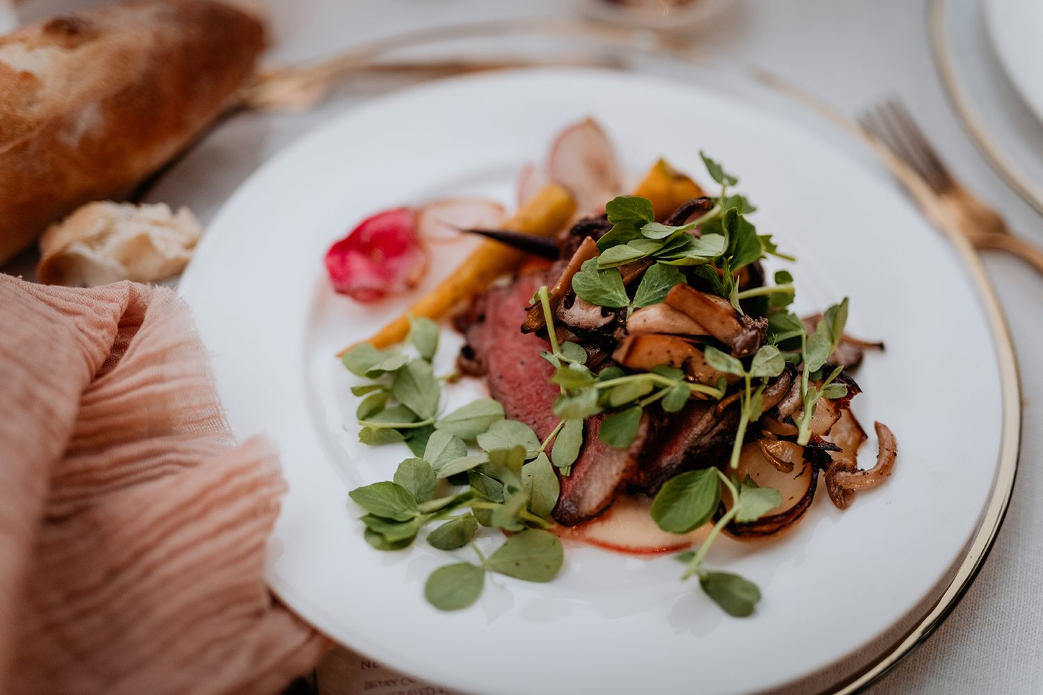 A white plate with sliced meat, sauteed mushrooms and fresh microgreens served with pickled radish garnish.