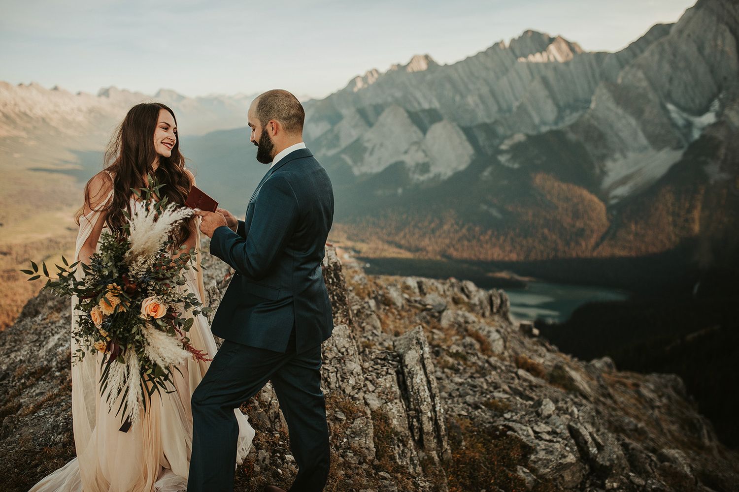 A couple shares an intimate moment during their mountain elopement ceremony with dramatic peaks in the background.