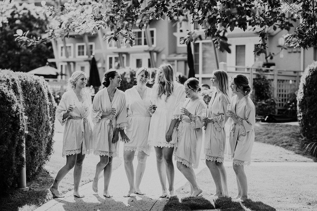 A bridal party in their morning robes walks together on a path through a garden or park setting.