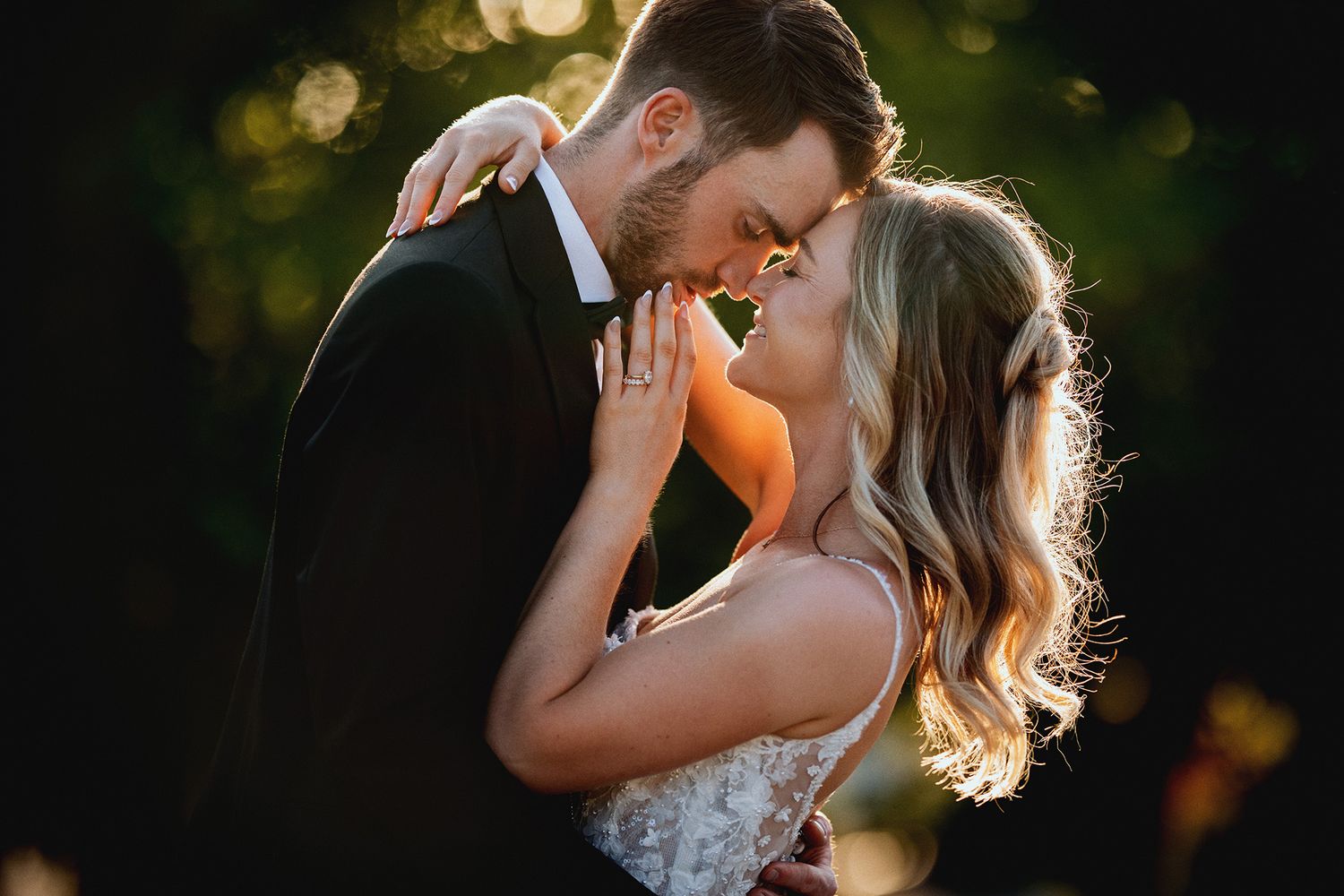 A romantic couple shares a tender kiss in a sunlit garden during a wedding celebration.