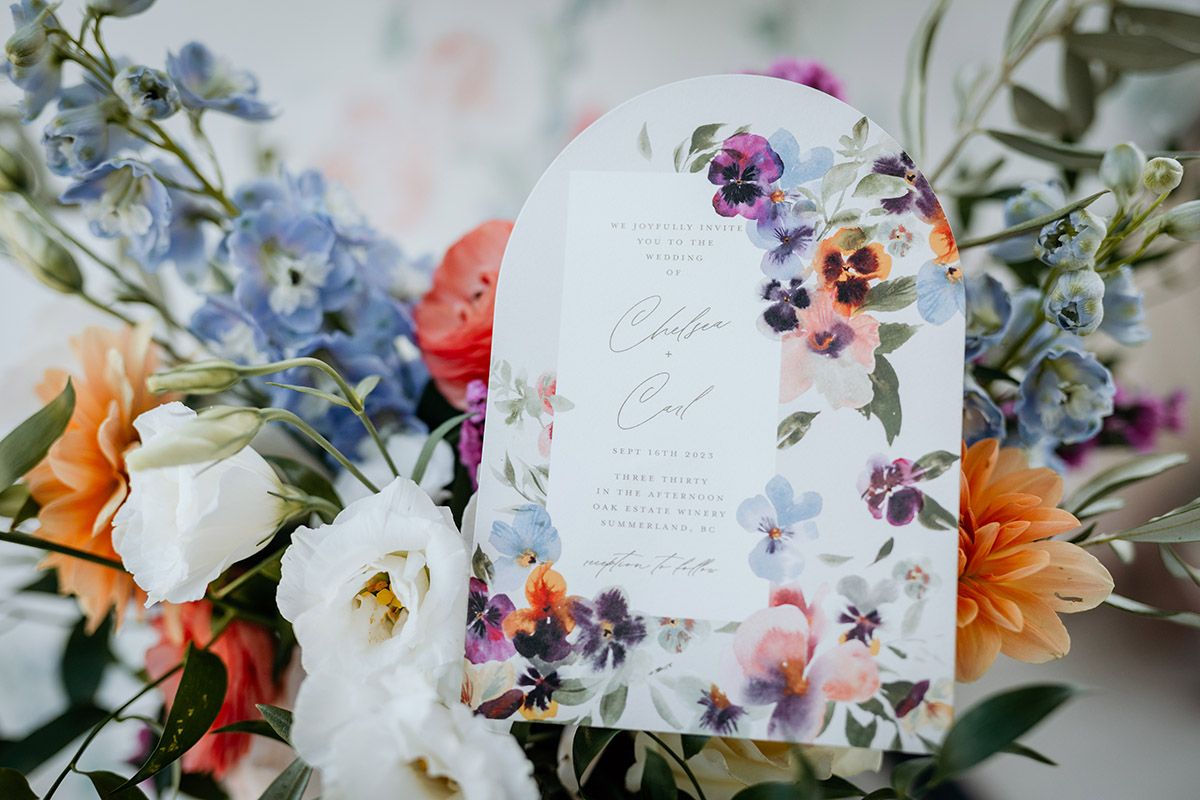 A romantic wedding table setting with delicate floral arrangements and white decor details against a soft blurred background.