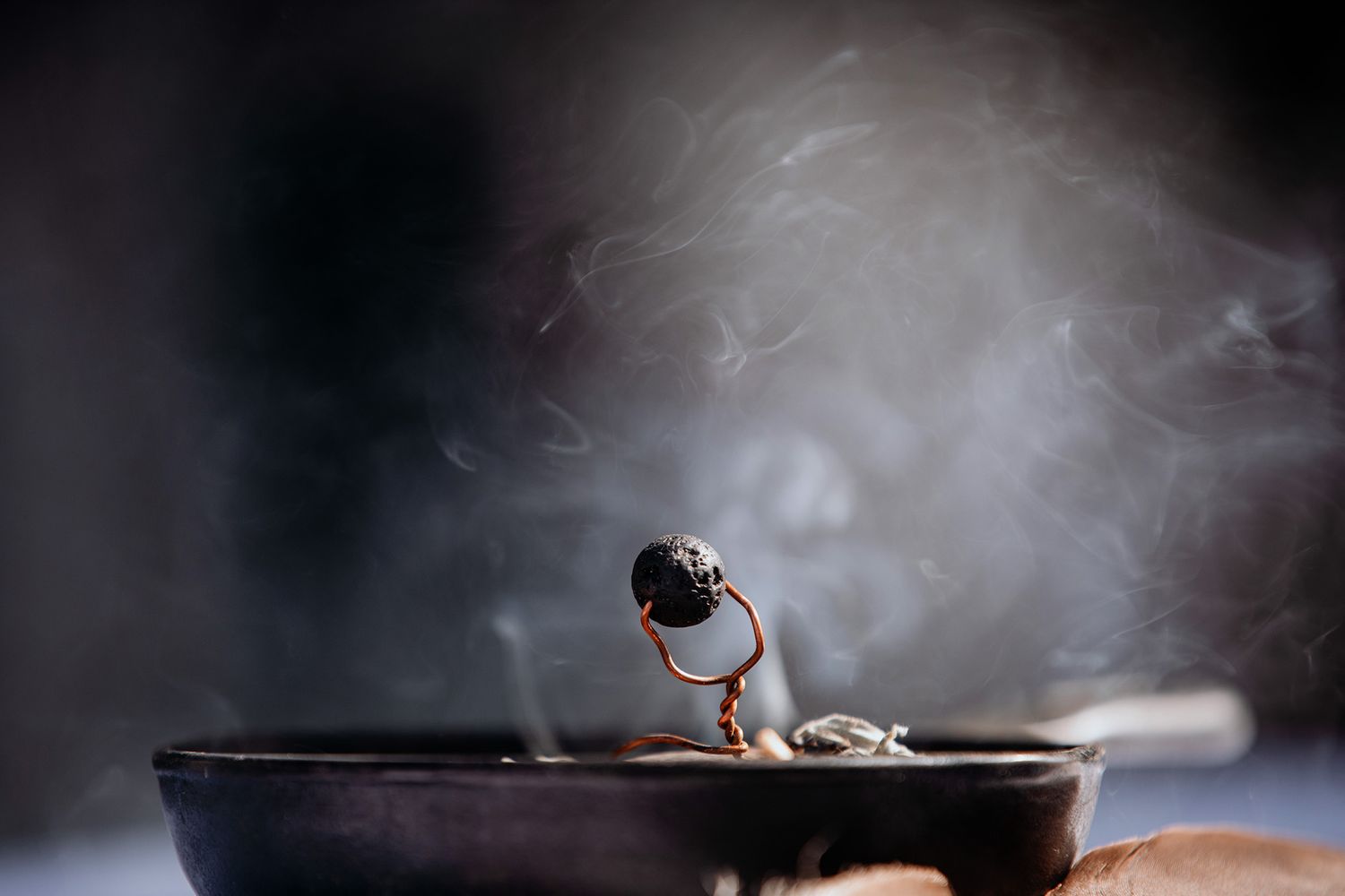 A smudge pot sits at a ceremony creating a dramatic moody atmosphere with smoke rising in the background.