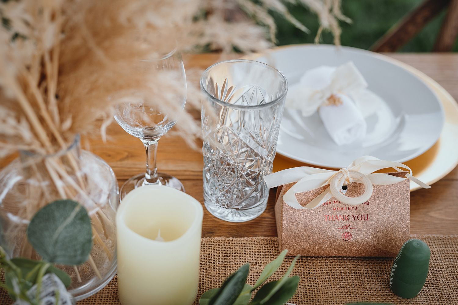 Crystal glassware and candles create an elegant table setting with natural greenery accents and soft lighting.