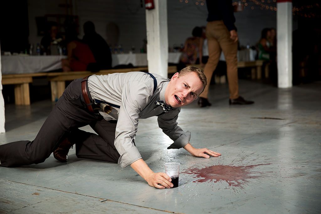 A wedding guest crouches on the dance floor, crying melodramatically over his spilled wine.