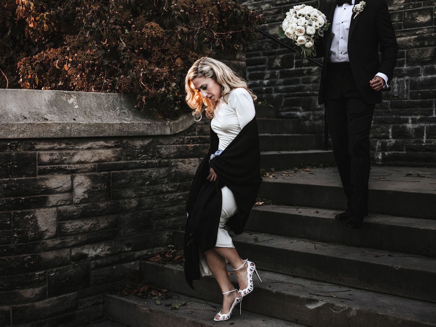 A couple in wedding attire dips gracefully on stone steps during their romantic outdoor photo session.