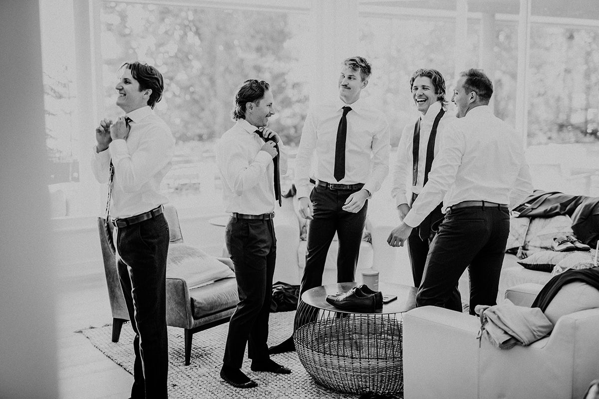 A black and white photo of a group of guys getting dressed before a wedding ceremony.