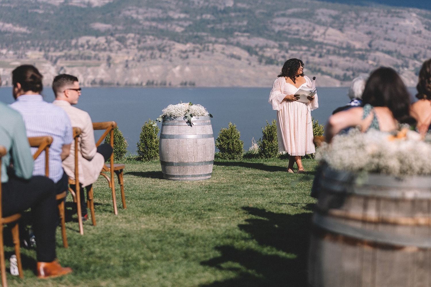 Outdoor wedding ceremony setup with wooden chairs and floral arrangements overlooking a scenic mountain lake view.
