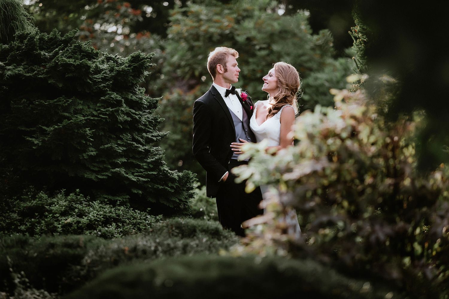 Romantic wedding couple embraces in a lush garden setting during an intimate outdoor photoshoot.