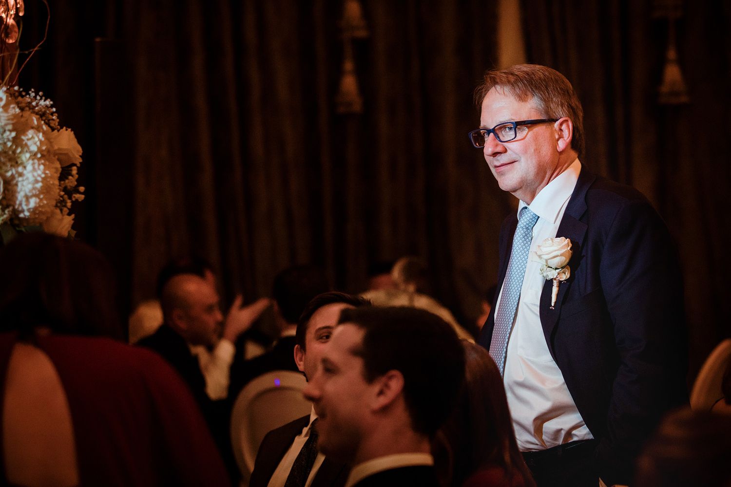 A group of formally dressed people engaged in conversation at an elegant evening event.