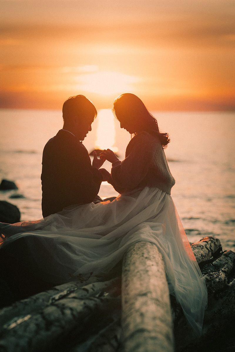 A romantic silhouette of a couple sharing an intimate moment against a golden sunset over the ocean.