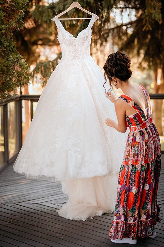 A white wedding dress hangs elegantly against a floral-patterned red dress in a series of artistic outdoor photos.