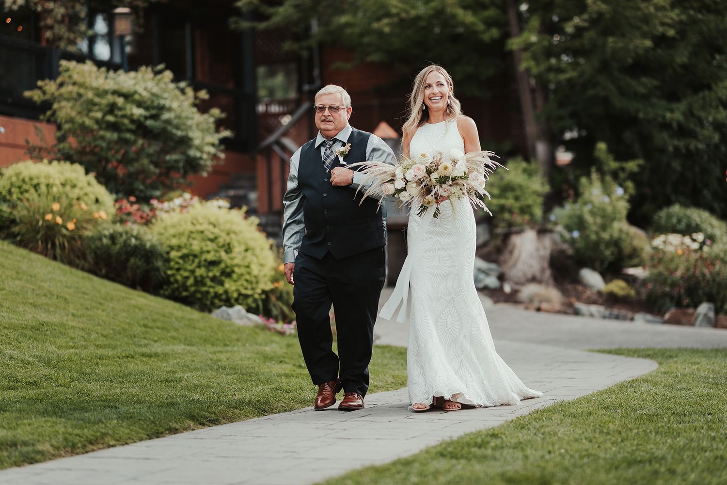 A bride's father escorts her down a garden path during their outdoor wedding celebration at Summerhill Pyramid Winery in Kelowna.