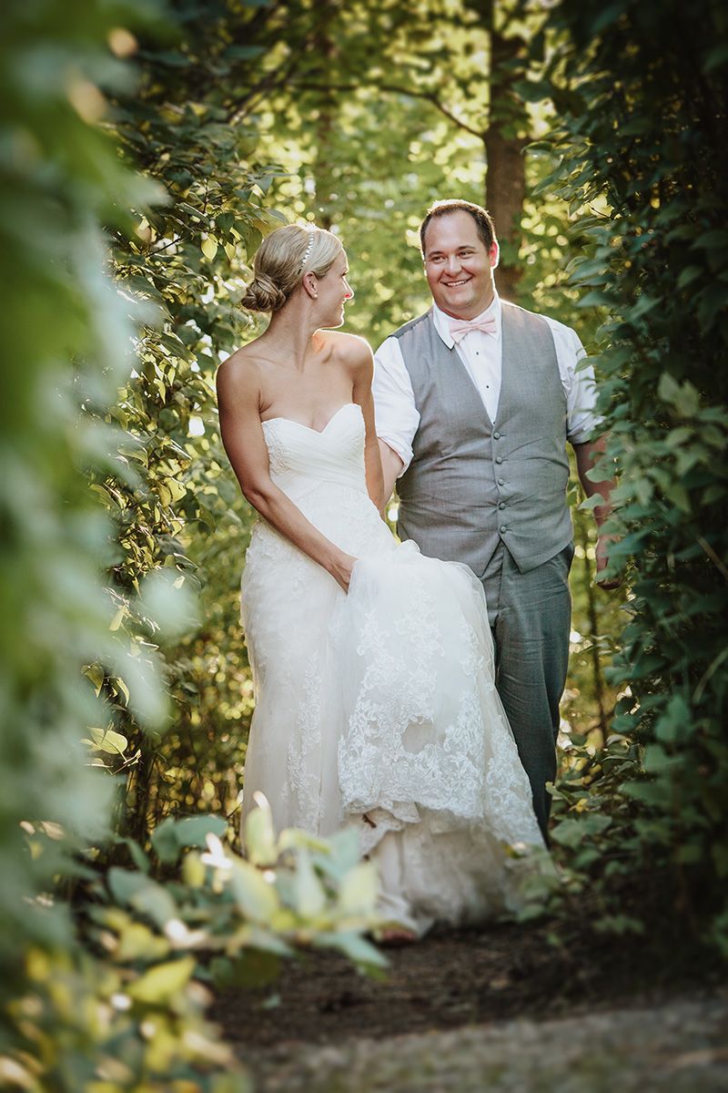 A couple shares a romantic moment on their wedding day surrounded by lush greenery in a forest setting.