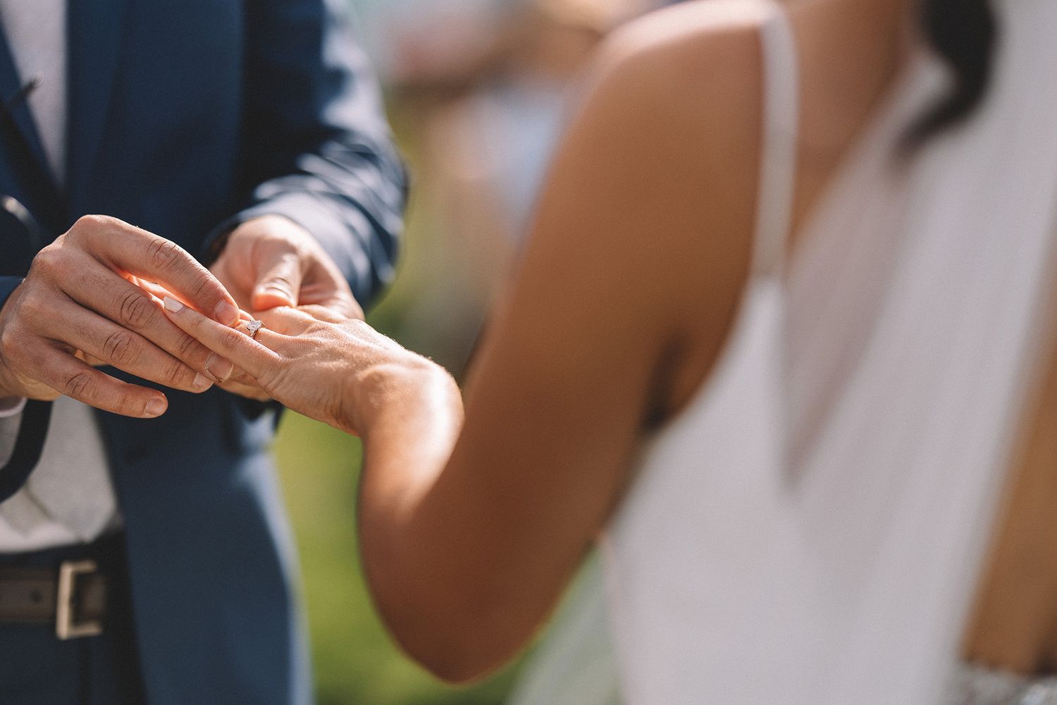 Two hands exchanging a business card in a professional setting against a blurred background.