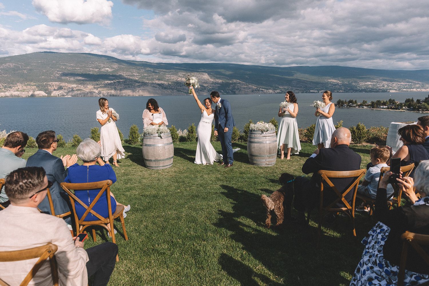 Panoramic view of an outdoor wedding ceremony on a hilltop overlooking mountains and valleys under cloudy skies.