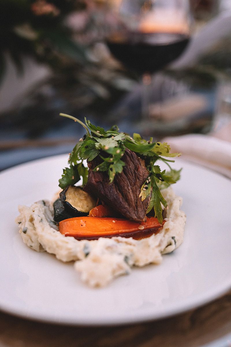Elegant plated dish with roasted vegetables and micro-greens served on a white plate with creamy sauce.