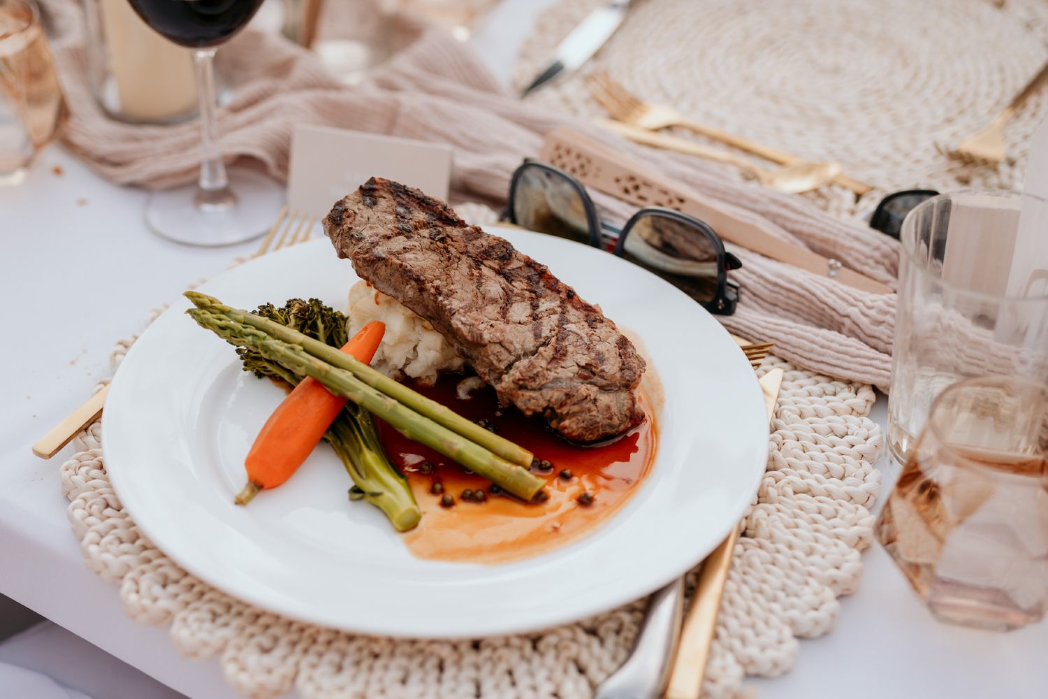 Elegant plated steak dinner with asparagus and carrots served on white plates in a fine dining setting.