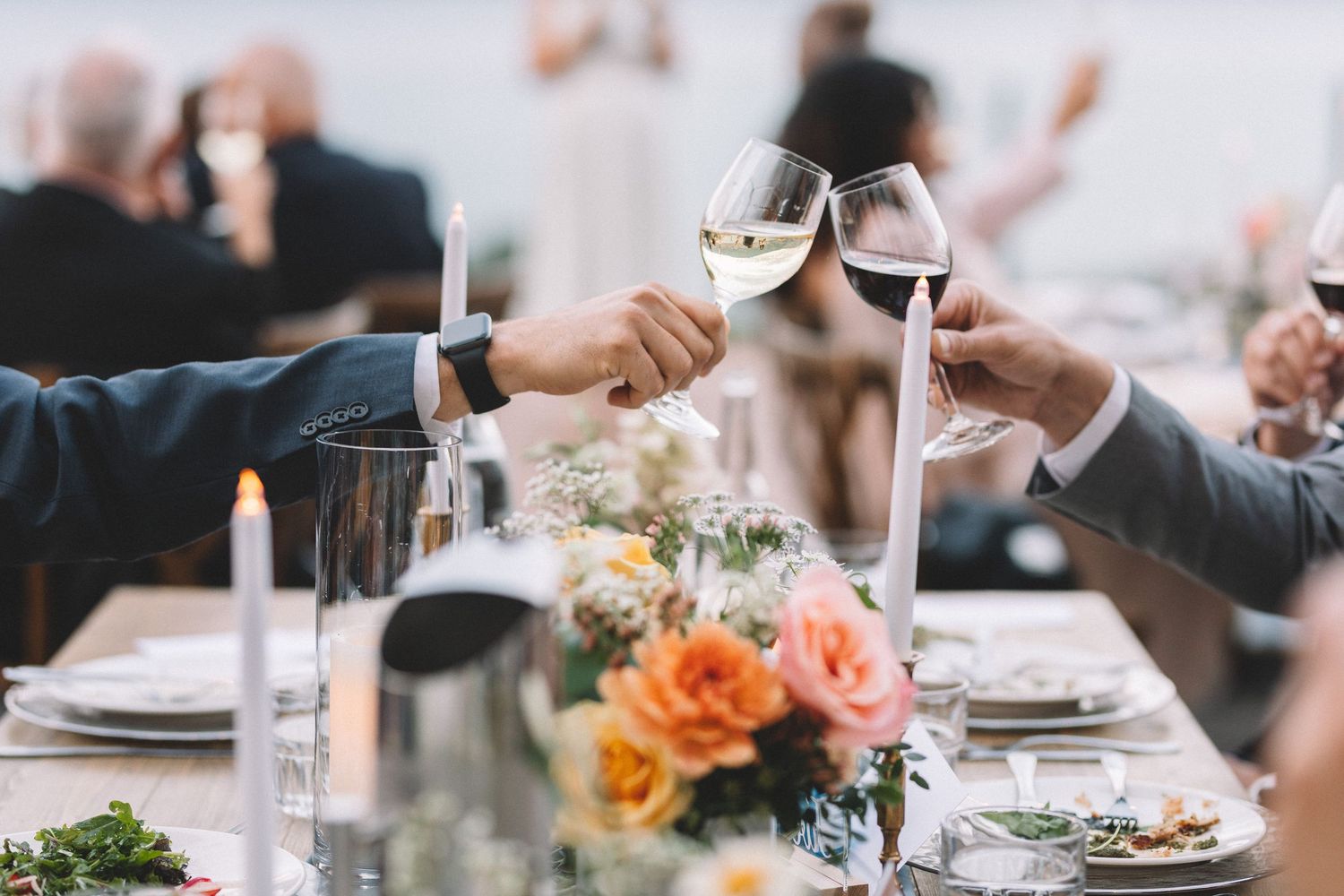 People enjoying a wedding reception with wine glasses and elegant table settings at Vows and Vines Vineyard.