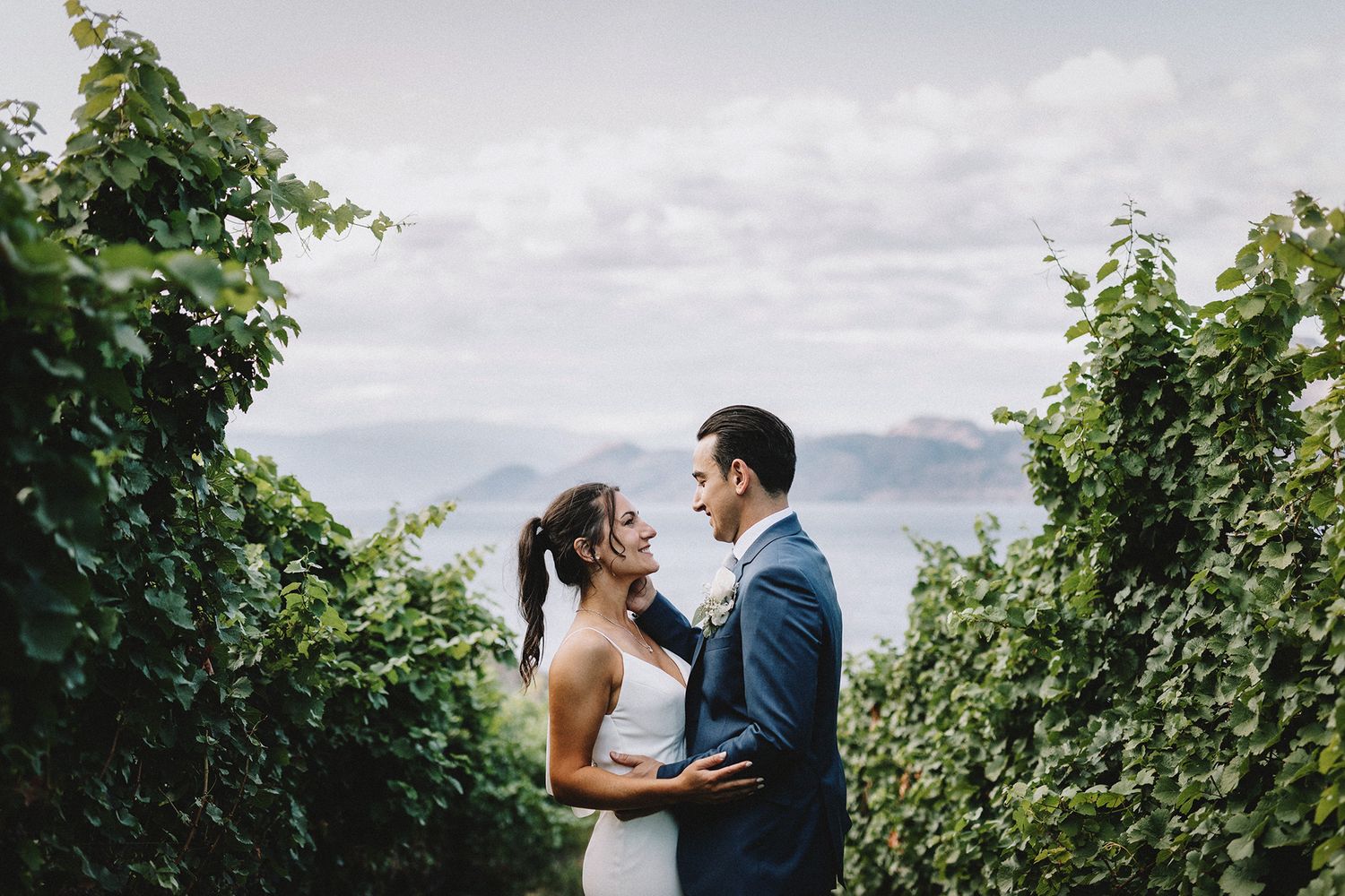 A couple shares a romantic moment in a lush vineyard setting during their wedding celebration.