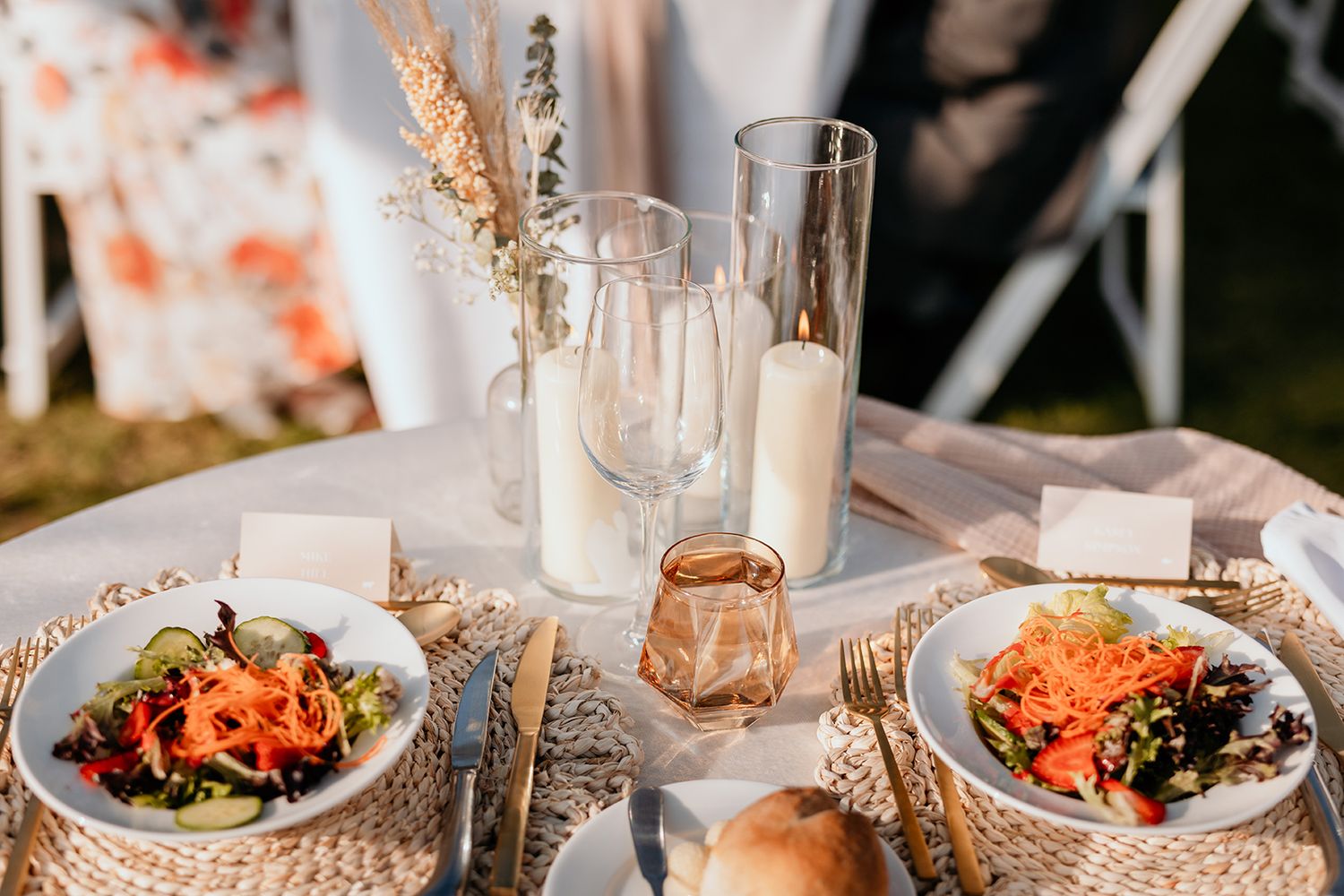 Elegant table settings with glowing candles and colourful salads served in white bowls at a formal dinner event.