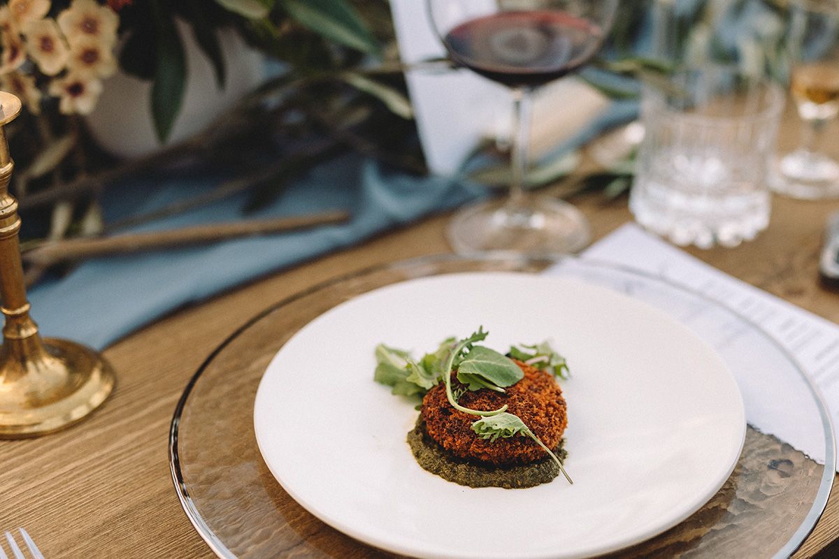 A series of elegant plated dishes on a wooden table showcasing fine dining presentation and culinary artistry.