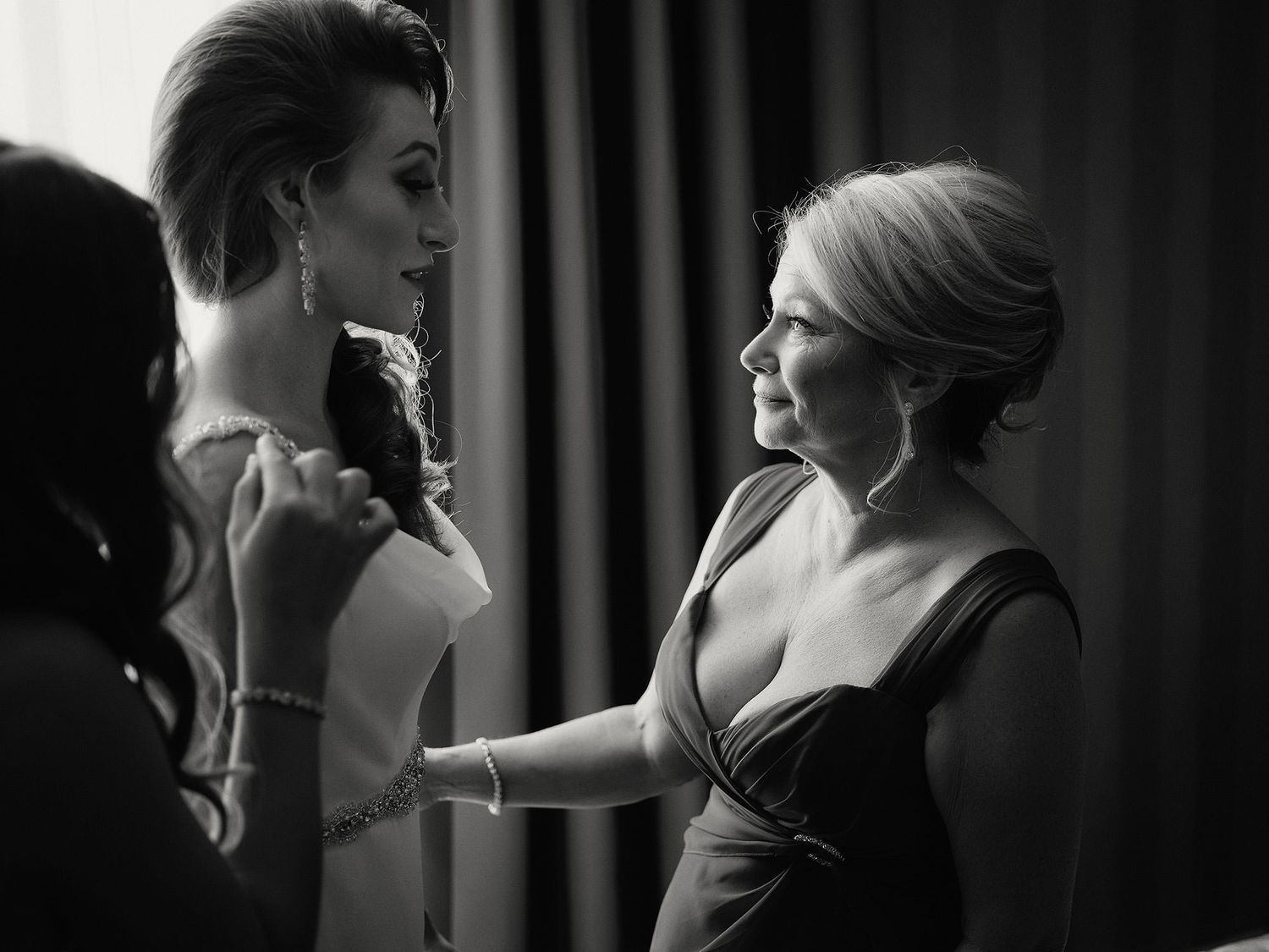 A dramatic black and white photo of a mother and her bride daughter in an intimate close-up with moody lighting.