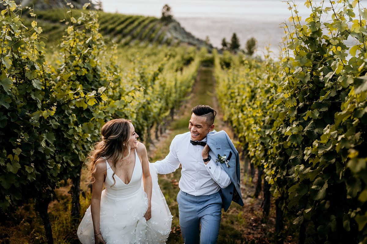 Couple shares an intimate moment in a sunlit vineyard with golden hills in the background.