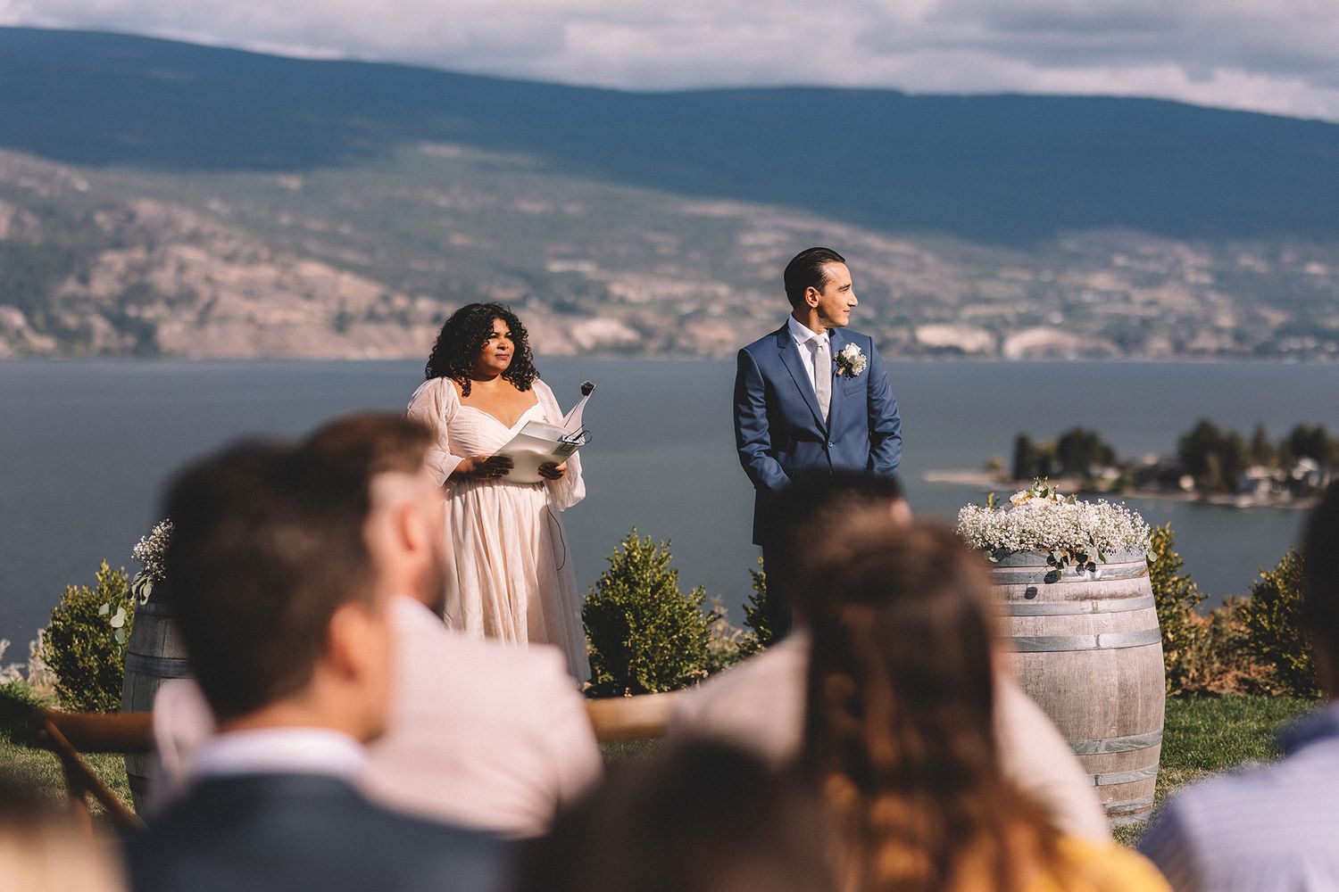 Scenic mountain wedding ceremony overlooking a serene lake with guests gathered under blue skies.