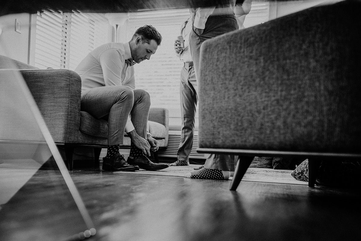 A low angle black and white photo of a man tying his shoe.