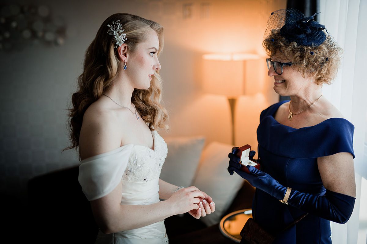 Two women in formal attire share an intimate moment during a wedding celebration with warm lighting.