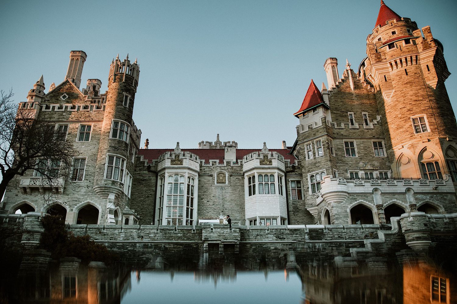 Casa Loma castle reflects in the water at dusk, showcasing its Gothic Revival architecture in Toronto, Canada.