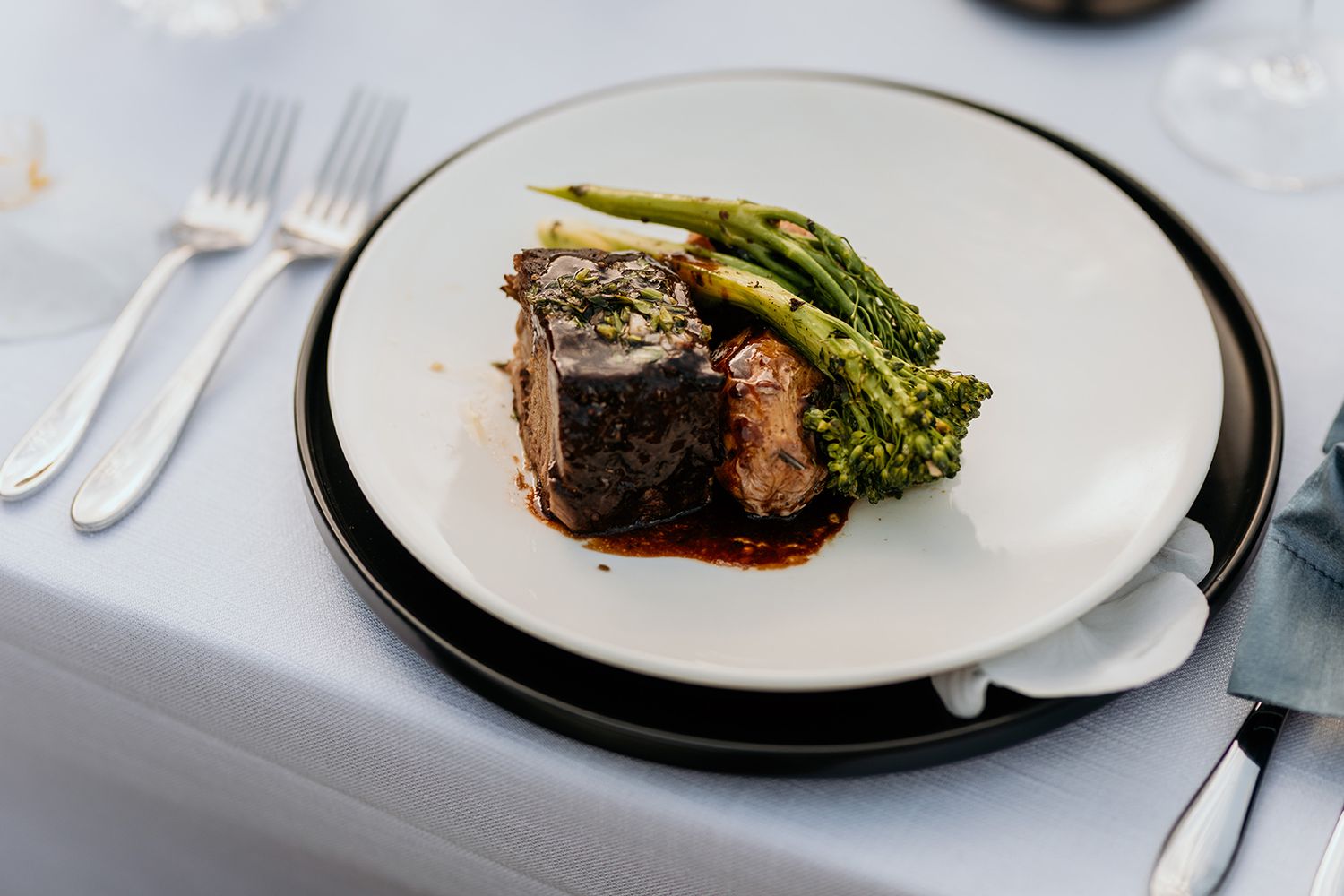 Elegant plated dishes featuring seared meat and vegetables served at an upscale wedding reception.