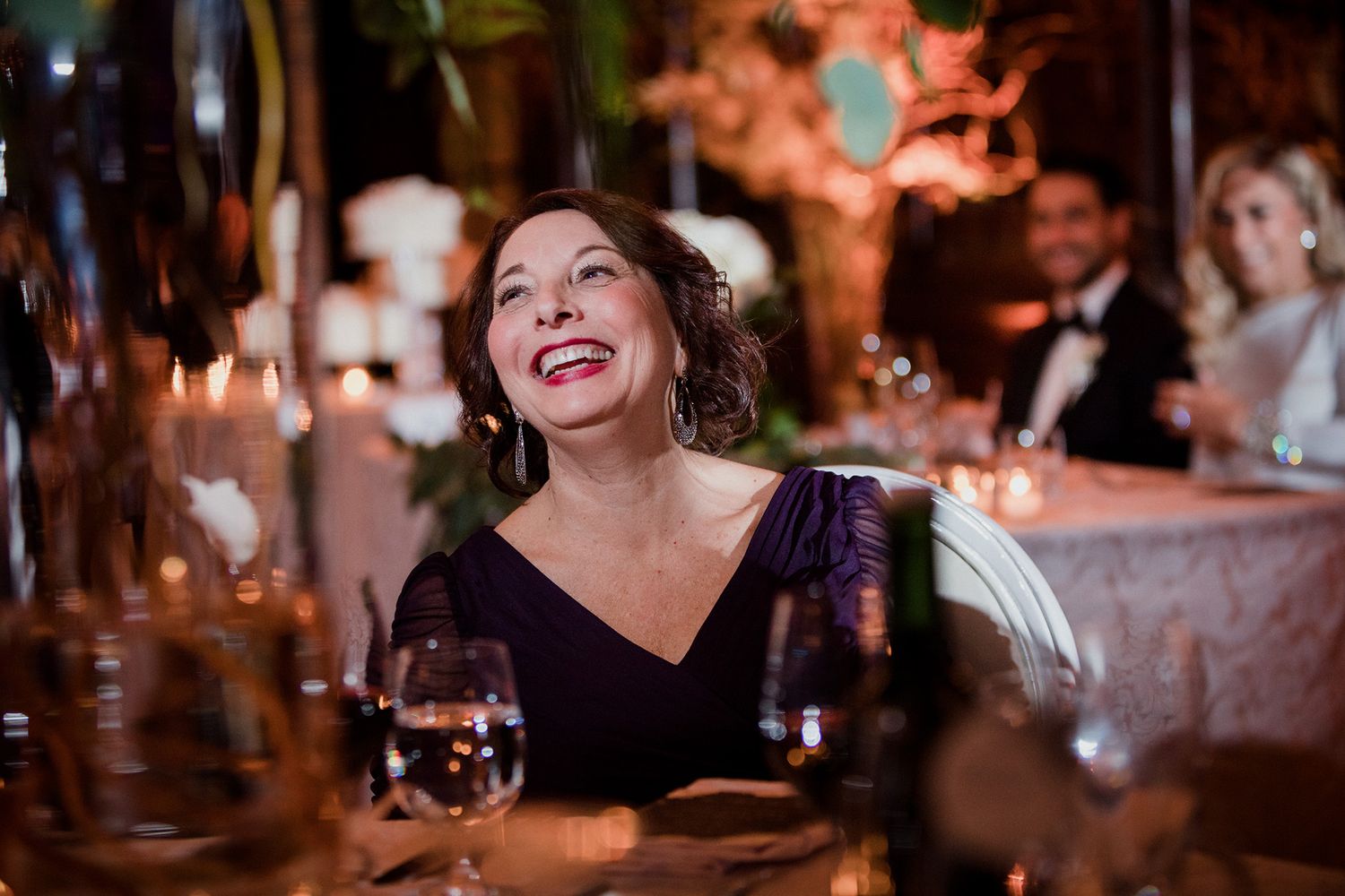 People enjoying a candlelit dinner party with wine glasses and warm ambient lighting.