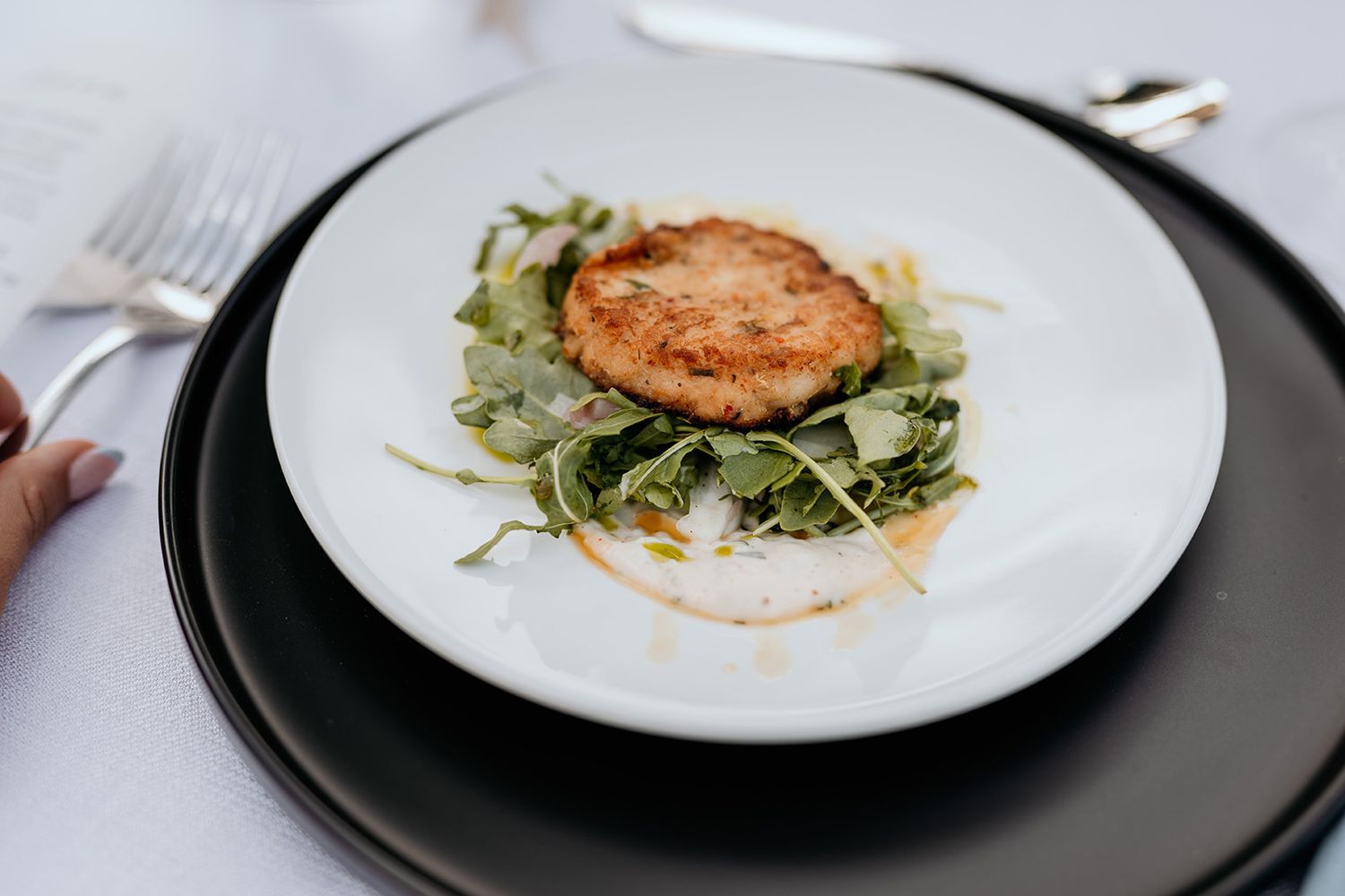 A series of white plates showing the step-by-step plating process of a gourmet salad with protein on top.