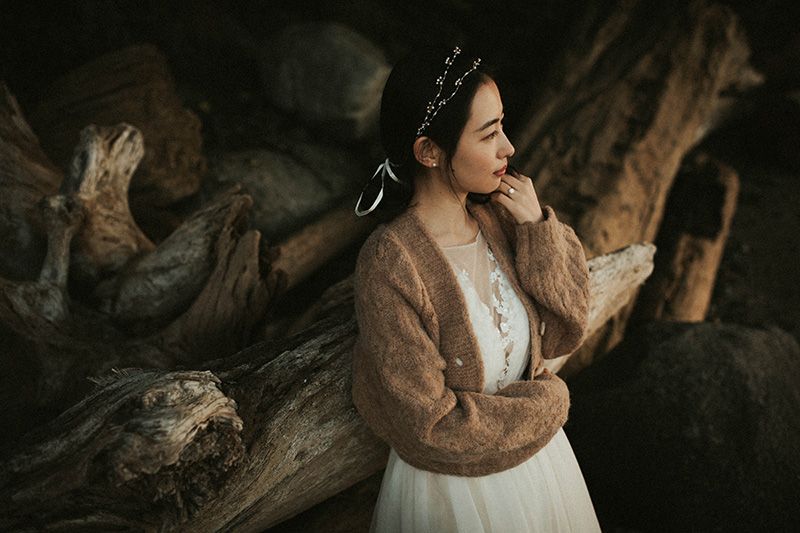 A couple embraces in a rustic setting surrounded by weathered wooden elements and natural textures.