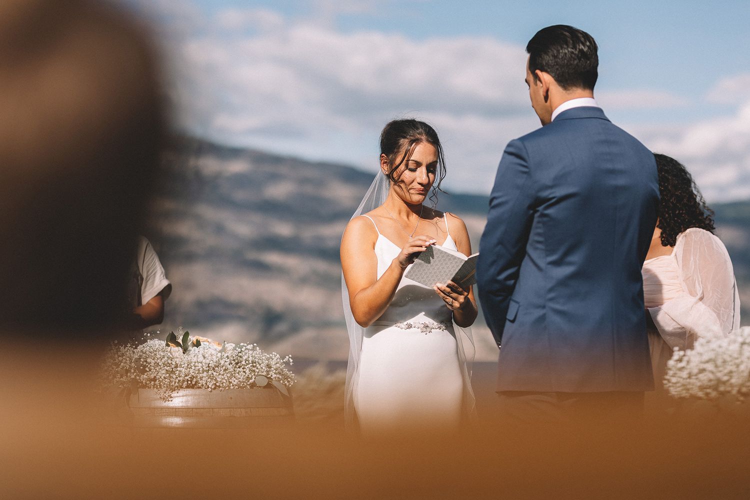 A couple shares an emotional moment during their outdoor wedding ceremony against a scenic mountain backdrop.