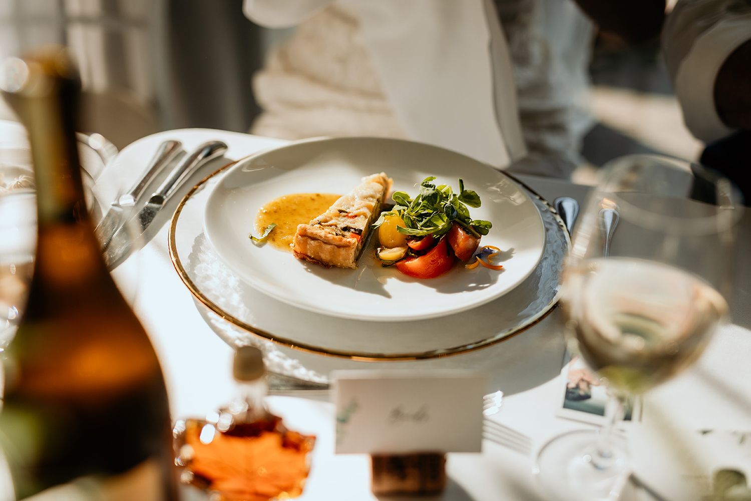 Elegant plated dishes on a decorated table with soft lighting and blurred background create an upscale wedding dining atmosphere.