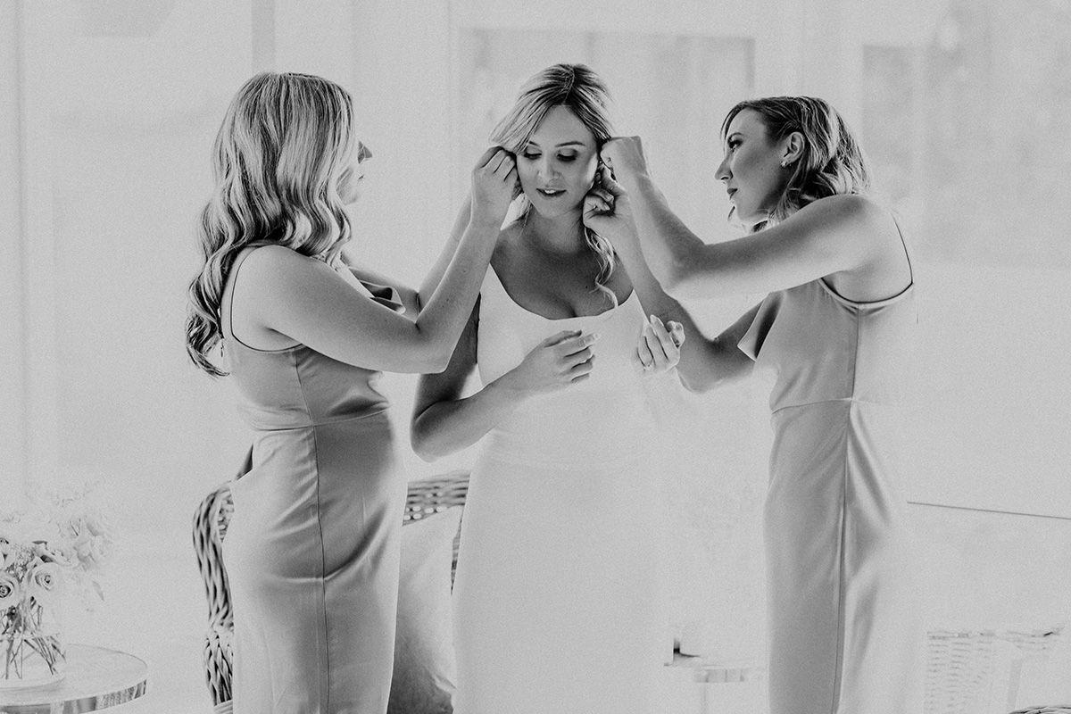 A black and white photo showing a bridal party getting ready and celebrating in a bridal suite.