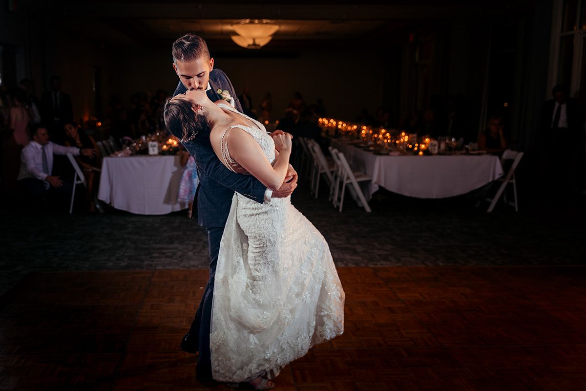 A couple shares their first dance as newlyweds on a dimly lit dance floor during their wedding reception.